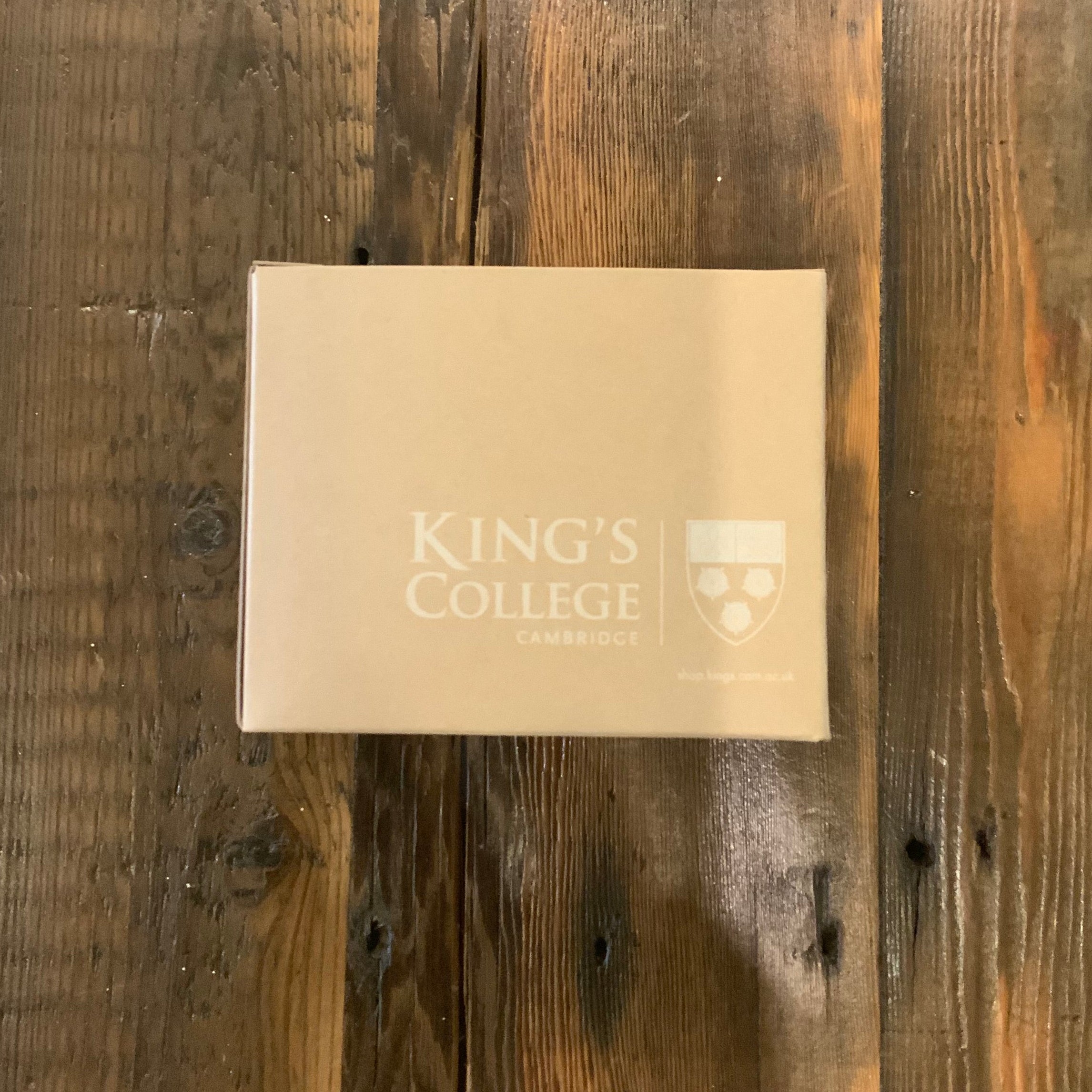 Beige box with 'King's College Cambridge' logo on a wooden surface